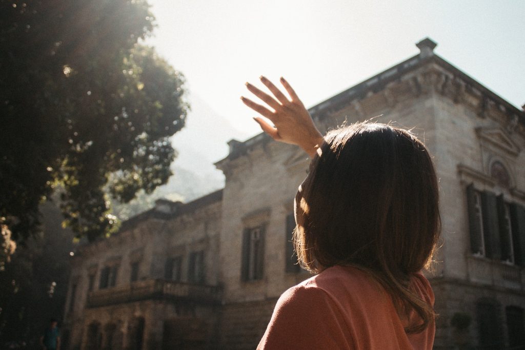 a woman reaching up into the air in front of a building