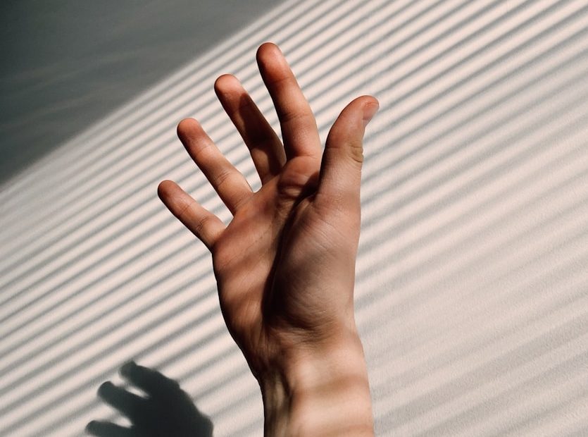 persons left hand on white window blinds